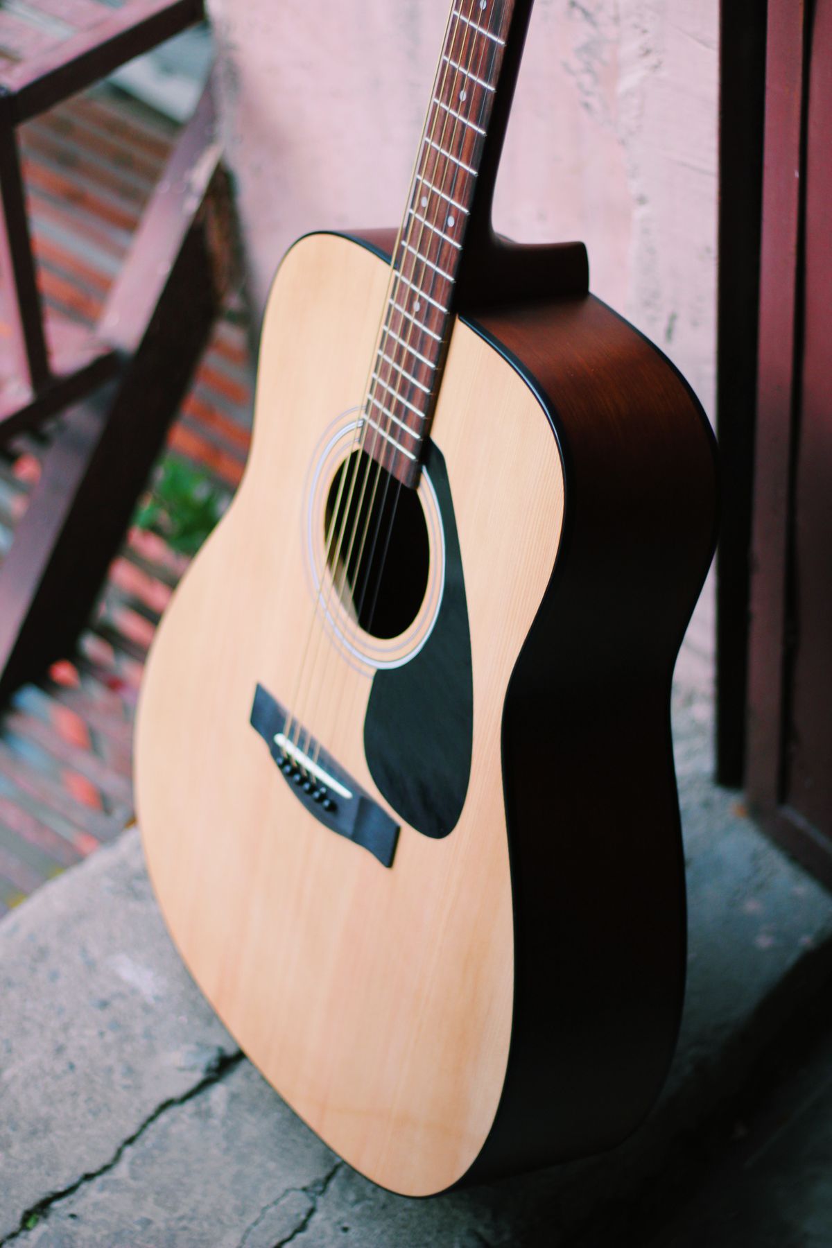 An acoustic guitar leaning against a wall